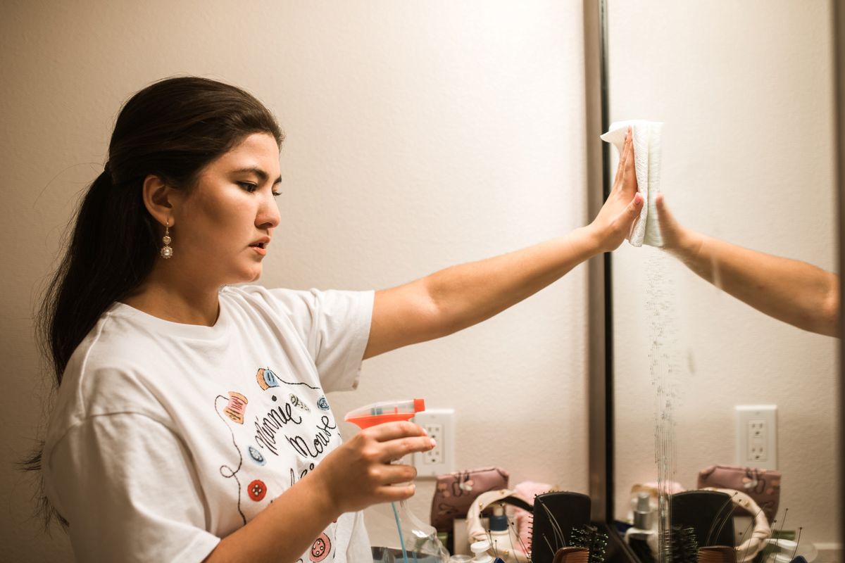 Housekeeper cleaning a mirror at home